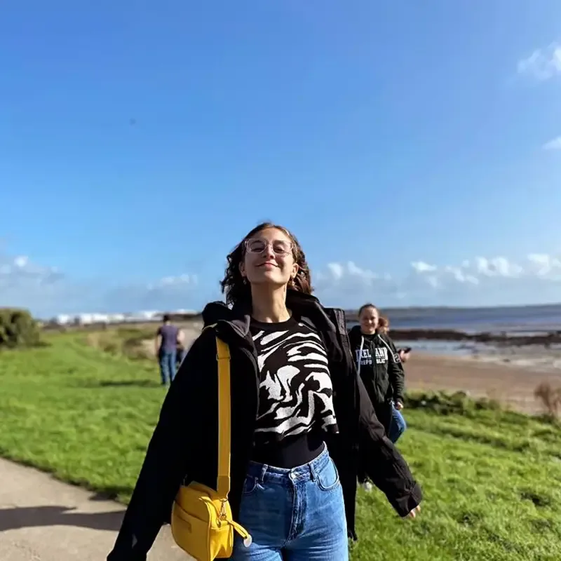 Studente cammina in una giornata di sole sulla costa irlandese, vivendo momenti di crescita e scoperta durante l'anno scolastico in Irlanda.
