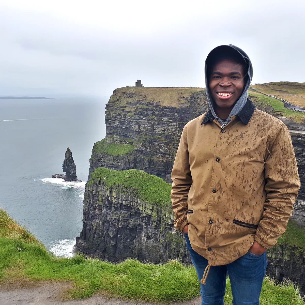 Studente sorride davanti a una scogliera irlandese, vivendo un’esperienza unica durante un anno all’estero in Irlanda, esplorando paesaggi naturali e culture diverse.